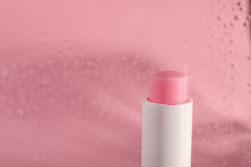 One lip balm on pink background, closeup. Space for text