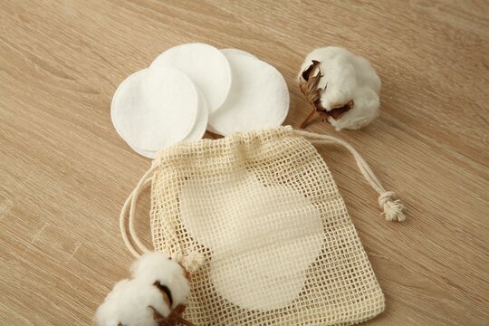 Cotton pads, bag and flowers on wooden table