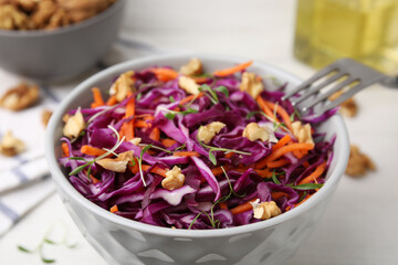 Tasty salad with red cabbage and walnuts at white table, closeup