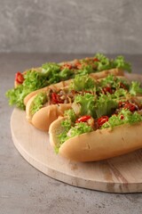 Tasty hot dogs with chili, lettuce and sauce on grey textured table, closeup
