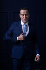 Portrait of handsome caucasian mexican man in formal suit looking at camera serious with toothy smile isolated blue background