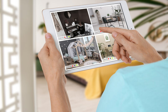 Woman using smart home security system on tablet computer indoors, closeup. Device showing different rooms through cameras