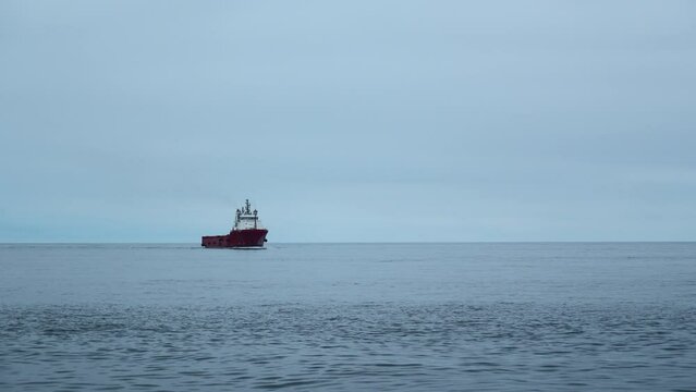 Floating ferry on background of cloudy sea horizon. Clip. Beautiful landscape with ferry in open sea. Ship on cruise in ocean in calm cloudy weather