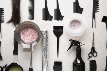 Bowls with hair dye and set of hairdresser's tools on white background