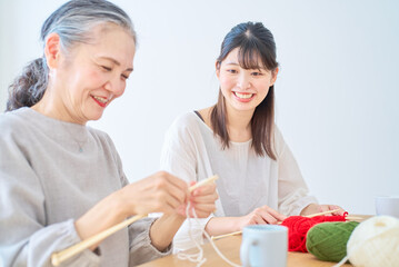 編み物をするシニア女性と若い女性
