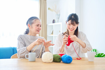 編み物をするシニア女性と若い女性