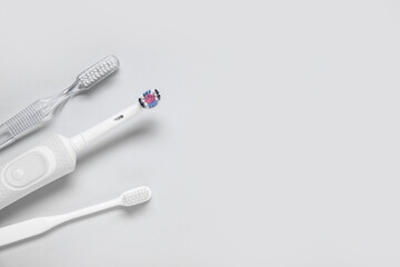 Electric and plastic toothbrushes on grey background.