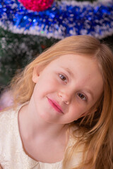  A beautiful elegant girl near the Christmas tree in the New Year. Holiday. New Year. The child is a model.