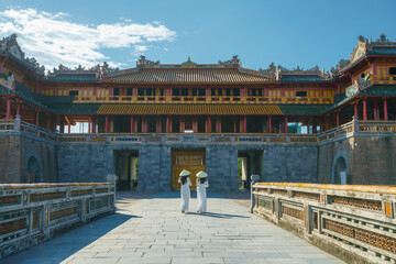 Ngo Mon gate - the main entrance of former Hue Imperial City in Hue city, Vietnam, with Vietnamese girls wearing traditional dress Ao Dai. Famous travel destination
