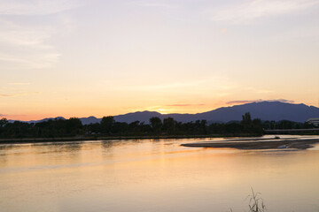 Aerial panoramic landscape with evening sunset over the river with islands and beautiful mountain clouds on golden yellow sky.