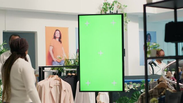 Green screen kiosk in luxury clothing shop advertising new collection of elegant formalwear clothes. Chroma key mockup digital display in fashion boutique used to promote store garments