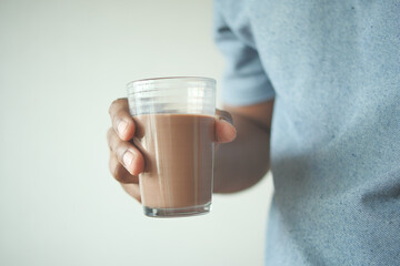 man hand holding glass of chocolate milk 