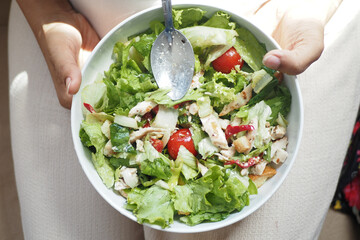 top view of women holding a bowl of fresh salad at home 