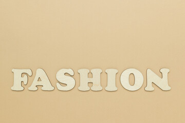 The fashion inscription is made of wooden letters on a beige background.