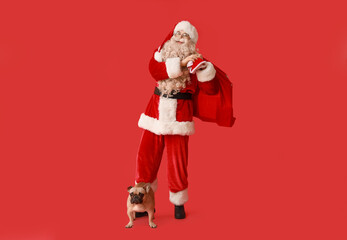 Santa Claus with bag and French bulldog on red background