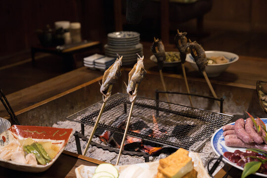 旅館などの旅行の食事で囲炉裏で魚を焼くところ　広角