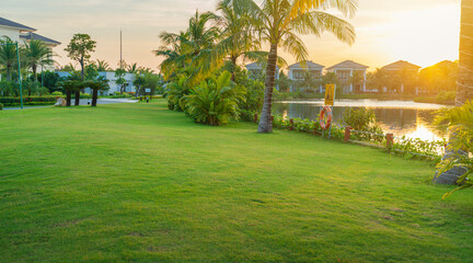 Vacation resort with grass field, green trees, early sunlight