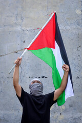 Young man waving the Palestine flag with raised hand
