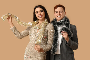 Young couple with Christmas tinsel on brown background