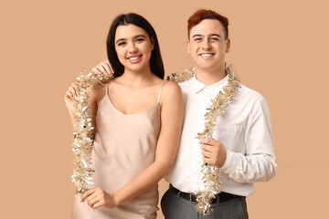 Young couple with Christmas tinsel on brown background