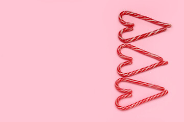 Hearts made of Christmas candy canes on pink background