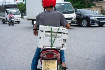 Used printer behind a man on motorbike in Hanoi street