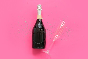 Champagne bottle and glass with Christmas decor on pink background