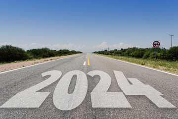 Año nuevo 2024 o concepto de inicio.. Palabra 2024 escrita en la carretera asfaltada en día radiante. Concepto de desafío y cambio. - obrazy, fototapety, plakaty