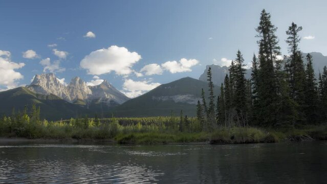 Three Sisters peaks and the lake on a summer day near Canmore, Alberta, Canada. Timelapse. 