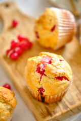 Muffins with red currants on a wooden board