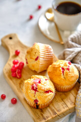 Muffins with red currants on a wooden board