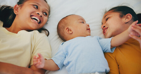 Happy family, love and sisters with baby on a bed for bonding, relax or conversation at home...