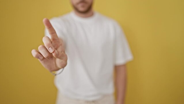 Young hispanic man saying no with finger over isolated yellow background