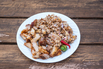 A serving of a piece of Liempo, or grilled pork belly, both chopped and whole and served with gravy.