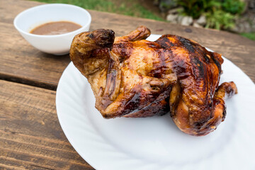 Delicious Lechon Manok, or spit-roasted chicken served outside at a bench with gravy.