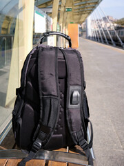 A lost or forgotten backpack on a bench on an open platform of a city metro.