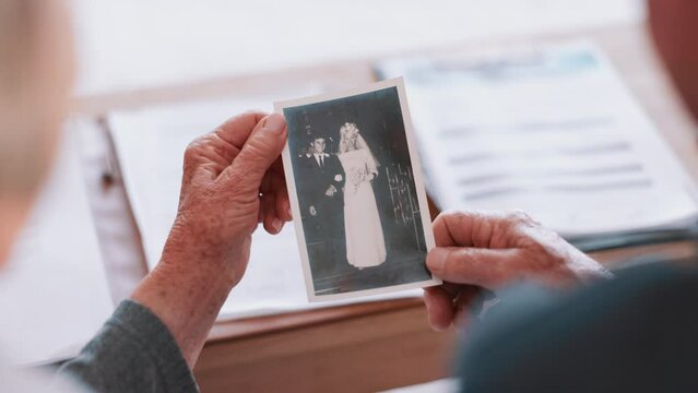 Photograph, memory and hands of old woman in home with husband and remember wedding and nostalgia for event. Elderly, couple and thinking of history together with vintage or retro picture in album