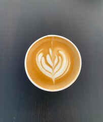 A cup of freshly prepared cortado coffee against a grey background