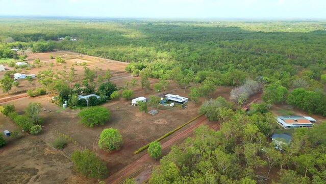Aerial of rural Australian family home. Establishing shot of bock of land with house, pool, shed, driveway and surrounding natural bush land. Beautiful scenic view.