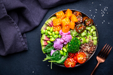 Vegan buddha bowl with pumpkin, quinoa, tomatoes, spinach, celery, radish, soybeans, edamame, tofu, cauliflower, broccoli and seeds, black table background, top view. Autumn or winter healthy food