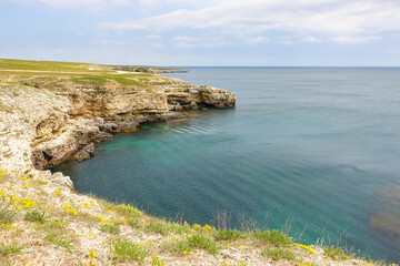 Cape Tarkhankut on the Crimean peninsula. The rocky coast of the Dzhangul Reserve in the Crimea. The Black Sea. Turquoise sea water. Rocks and grottoes of Cape Tarkhankut.
