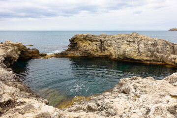 Cape Tarkhankut on the Crimean peninsula. The rocky coast of the Dzhangul Reserve in the Crimea. A sunny summer day. The Black Sea. Turquoise sea water.
