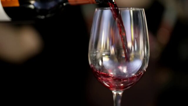 waiter pouring red wine into wine glass in restaurant, dinner or party in bar, closeup view