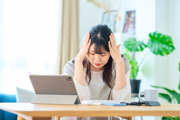 部屋でパソコン操作中にストレスを感じる女性