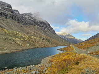Golden autumn in the Arctic mountains beyond the Arctic Circle. View of a beautiful lake and yellow birches. Mountain peaks in the background. Autumn in the mountains of Khibiny.