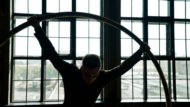 silhouette of mysterious man in black cloak spinning in hoop, slow motion shot