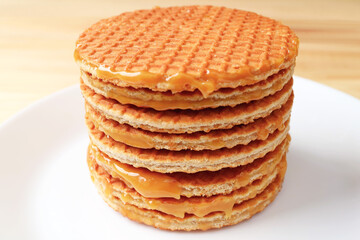 Stack of Mouthwatering Stroopwafels on the White Plate Served on Wooden Table
