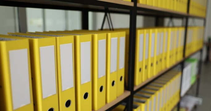 Yellow folders with tax documents in rows on shelves