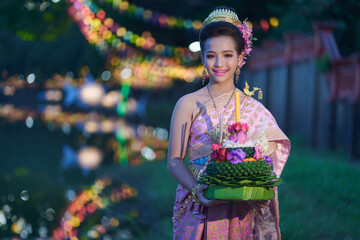 Pretty Asian women holding beautiful Krathong is handmade from banana leaves, flowers, candles...