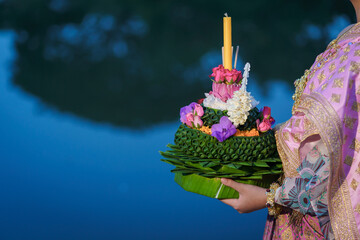 Hand-carrying beautiful Krathong is handmade from banana leaves, flowers, candles incense sticks, and a river for the Loy Krathong festival in Thailand.